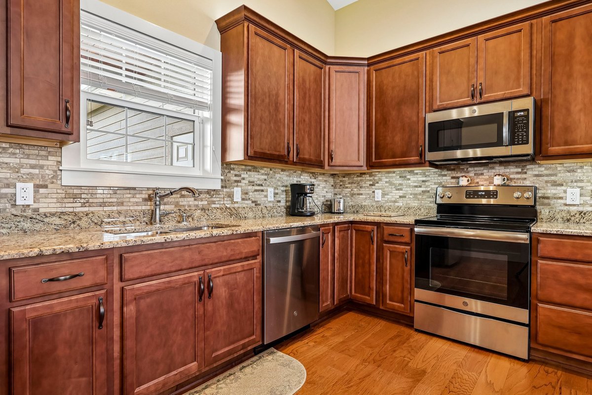 Kitchen appliances, granite countertops, backsplash, and wood cabinets in Haines City home