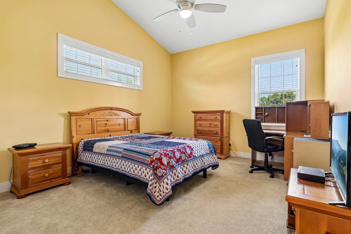 Bedroom with vaulted ceiling, carpet, wood furniture, and natural light in Haines City home