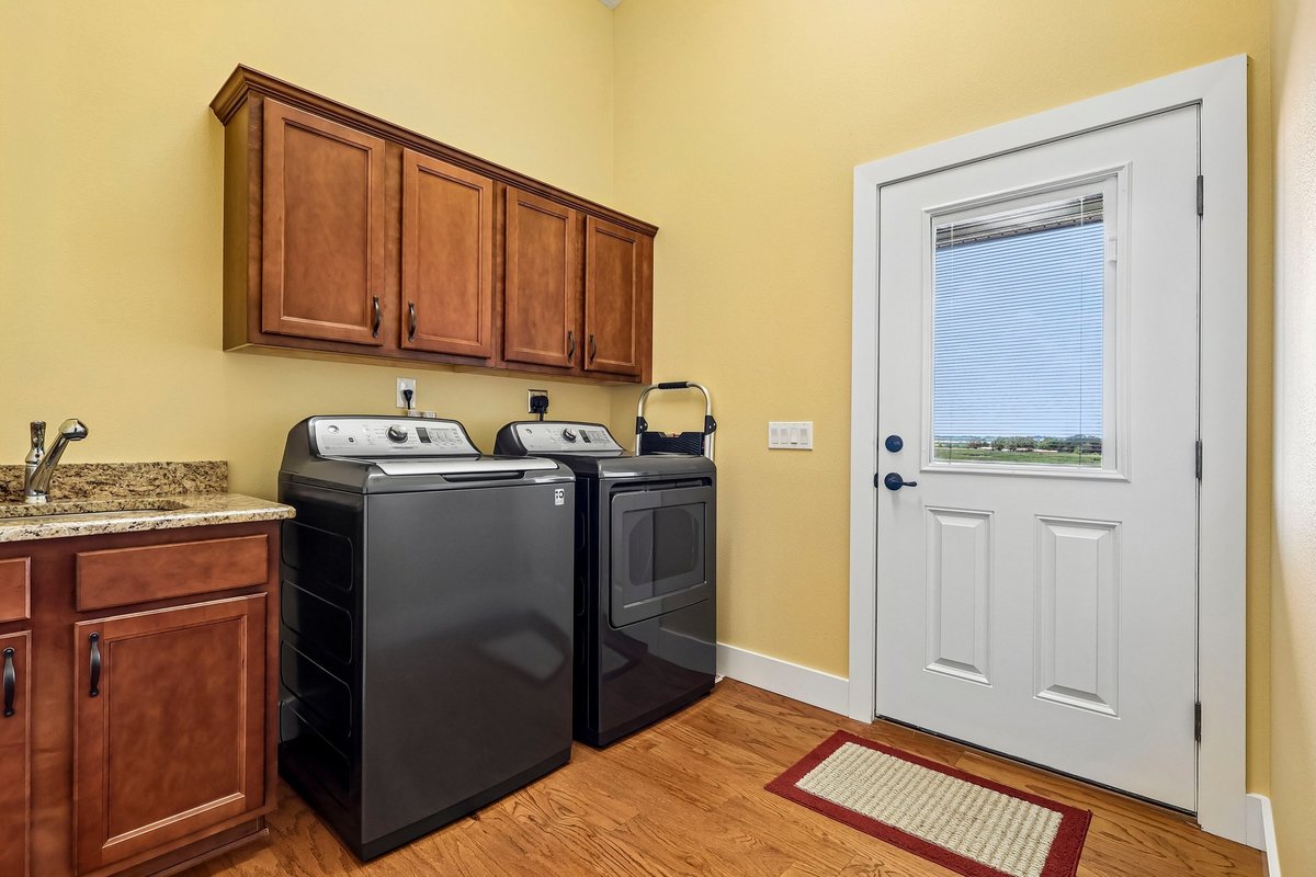 Laundry room with washer, dryer, storage cabinets, sink, and exterior door