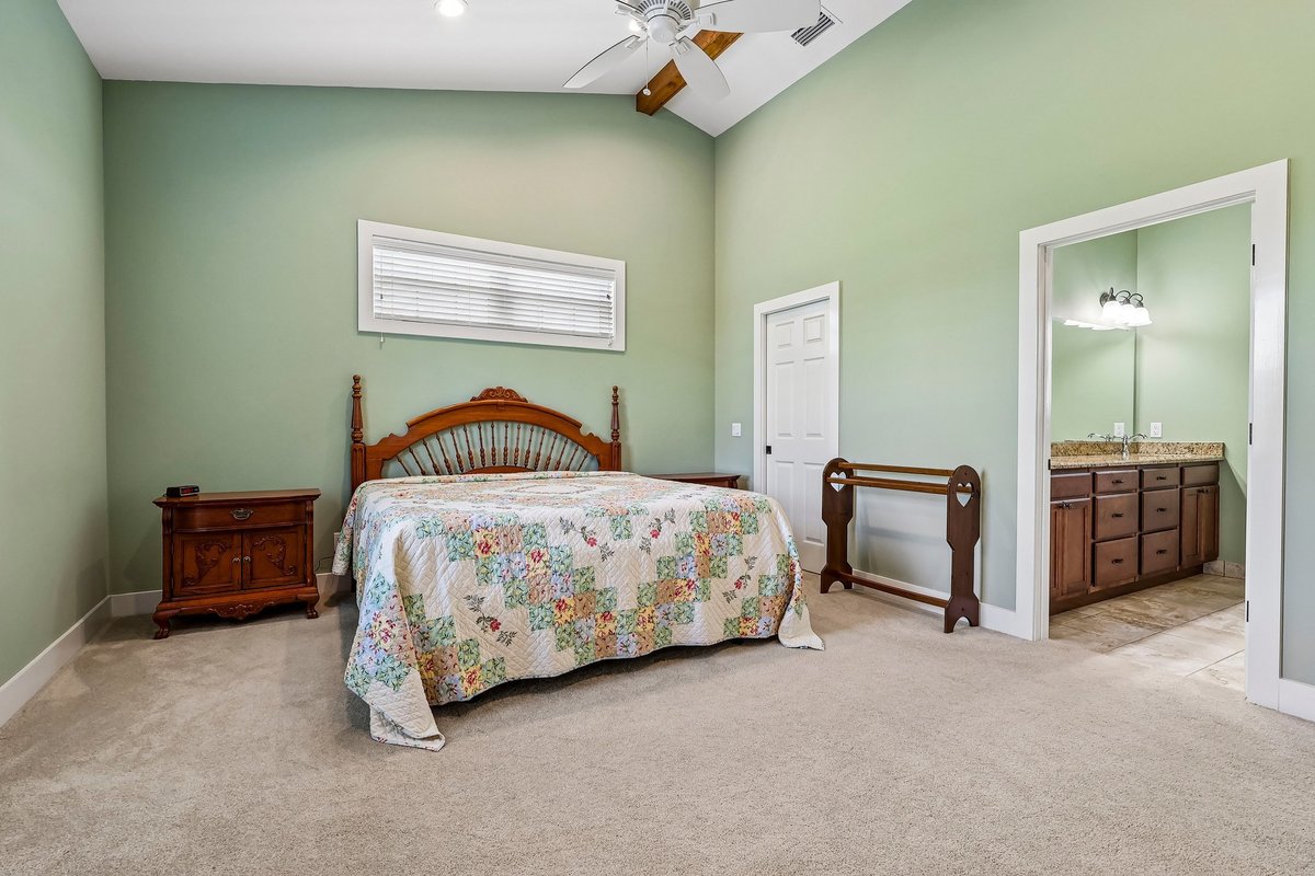 Bedroom with vaulted ceiling, carpet, wood furniture, and natural light in Haines City home