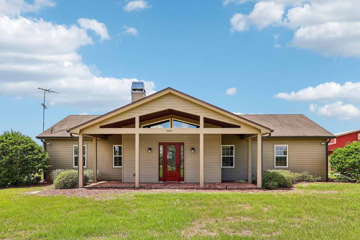 Front exterior of custom-built Haines City home with covered entry and red front door