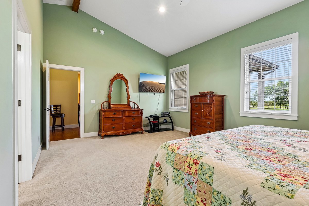 Bedroom with vaulted ceiling, carpet, wood furniture, and natural light in Haines City home