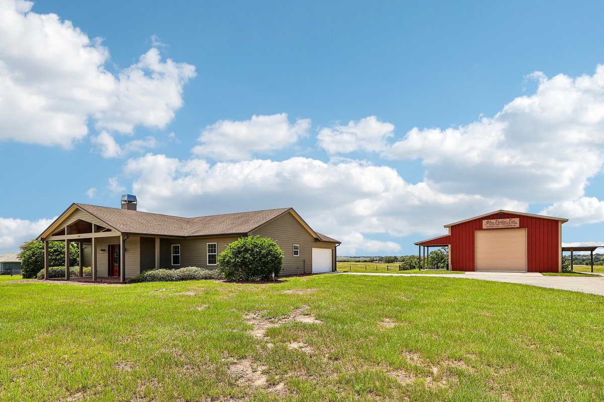 Wide exterior view of Haines City acreage property with custom home and red workshop building