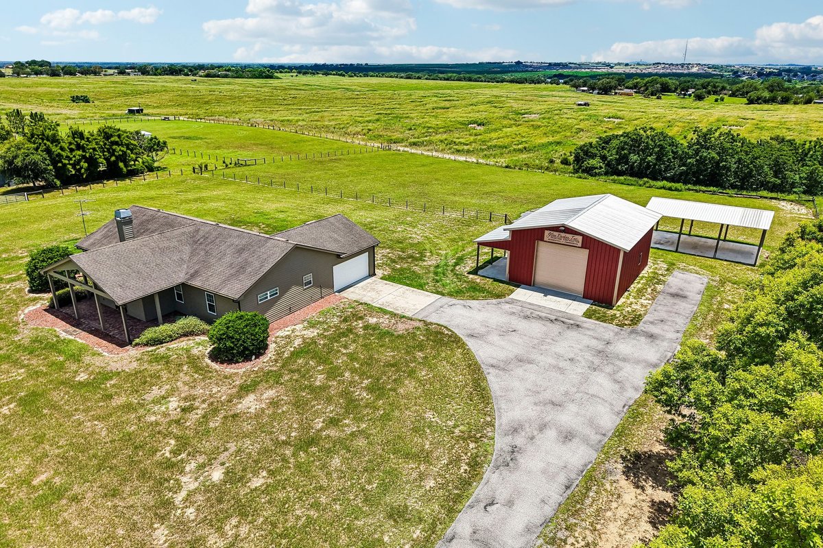 Front elevation of custom Haines City home with covered porch, red door, and lawn