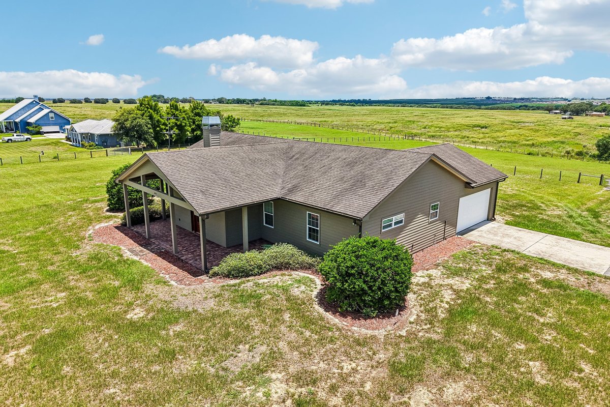Front elevation of custom Haines City home with covered porch, red door, and lawn