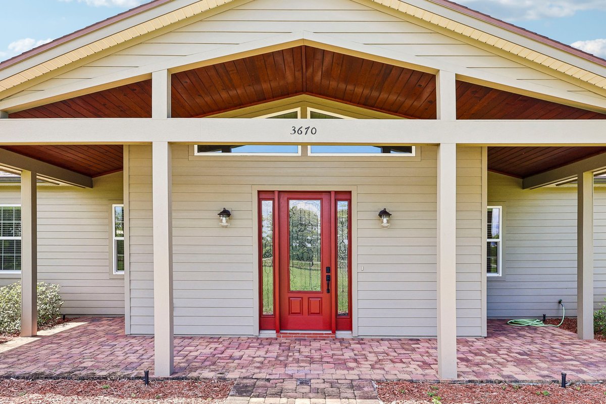 Close-up of covered front entry with red door at custom Haines City acreage home