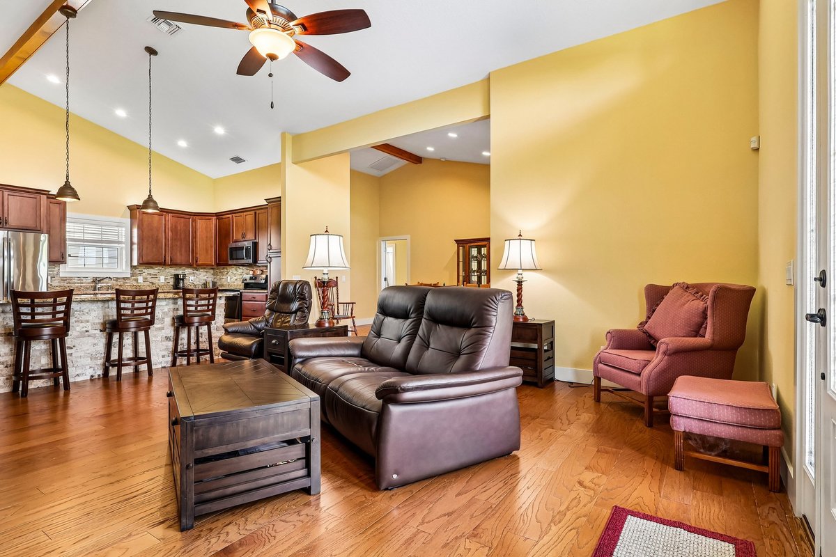 Open living room with wood floors, high ceilings, fireplace, and leather seating in Haines City home