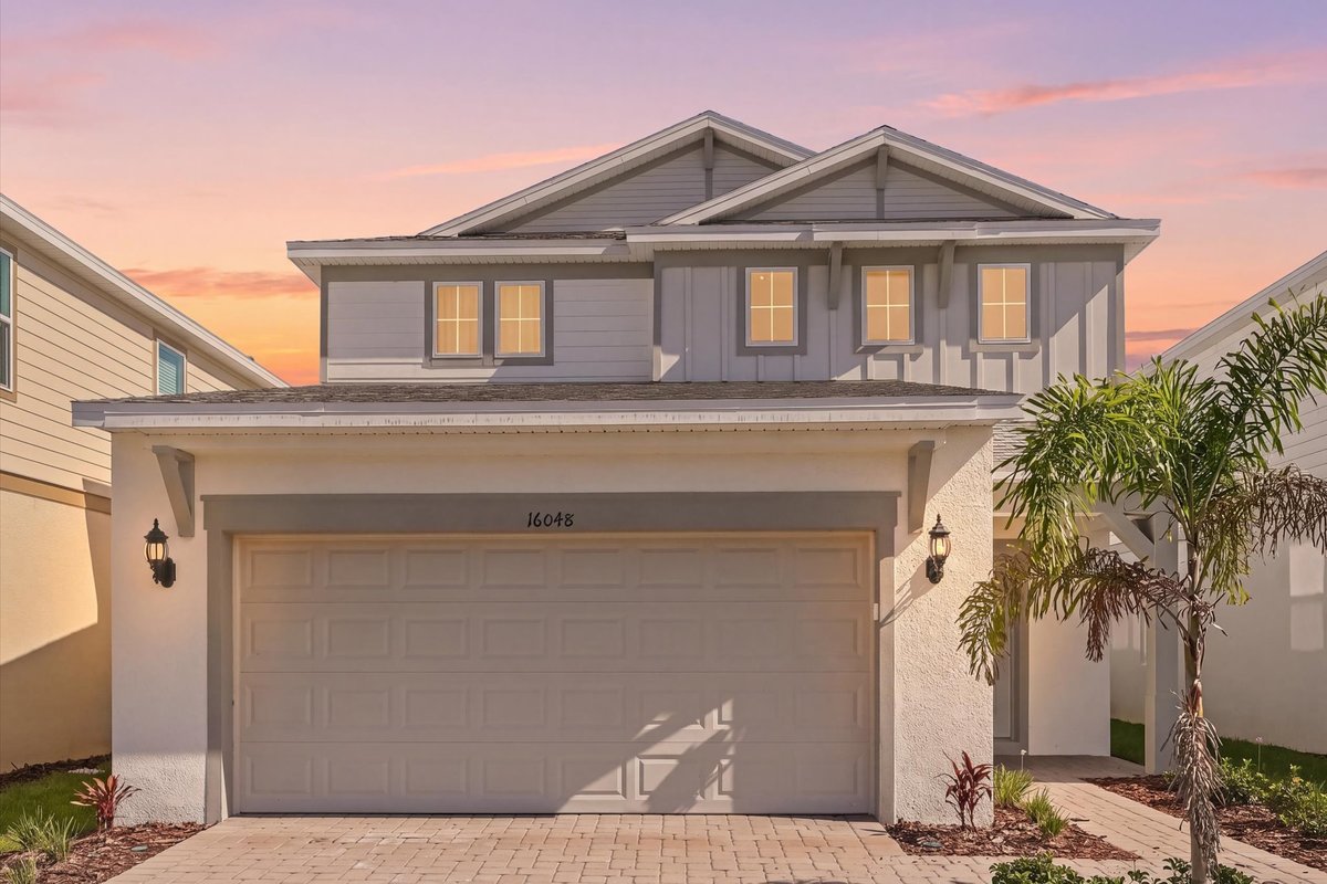 Virtual twilight exterior of a modern Windsor Cay vacation home with warm interior lights and palm landscaping.