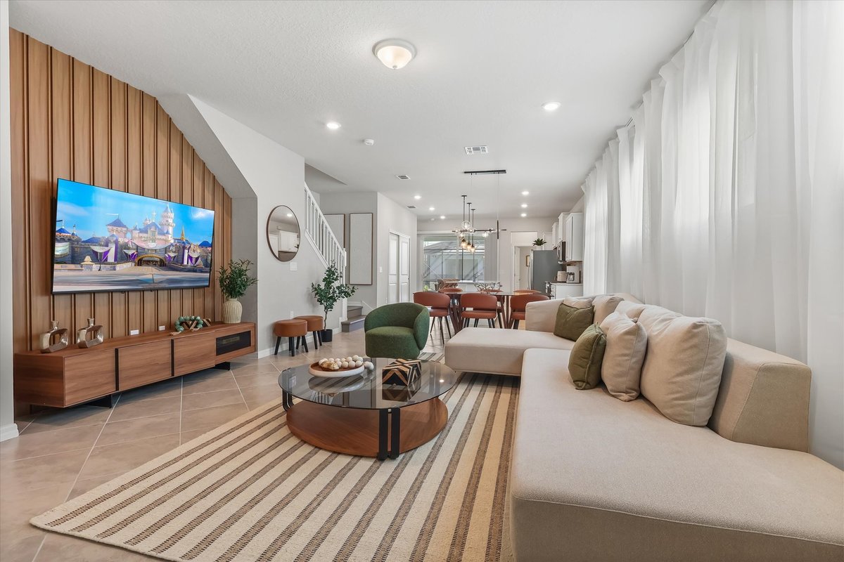Bright open-concept living room with neutral seating, wood accent wall and views toward the dining area.