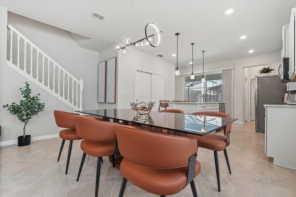 Contemporary dining area with rust-toned chairs, modern lighting and an open connection to the kitchen.