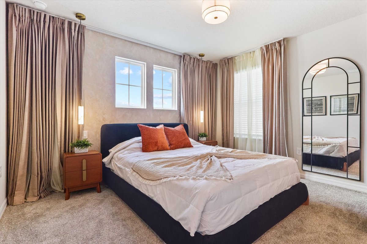 Blue-accent bedroom with layered curtains, modern mirror and warm terracotta decor in a soft neutral palette.
