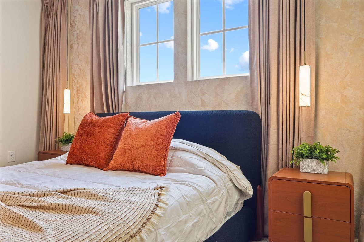 Bedroom detail with blue upholstered headboard, terracotta pillows, natural light and warm bedside accents.