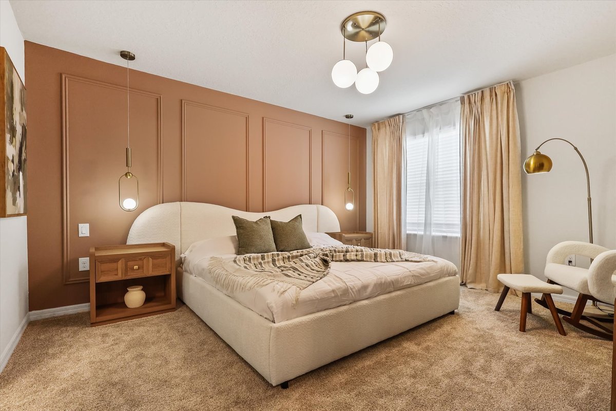 Spacious bedroom with terracotta feature wall, upholstered bed, modern lighting and a reading corner.