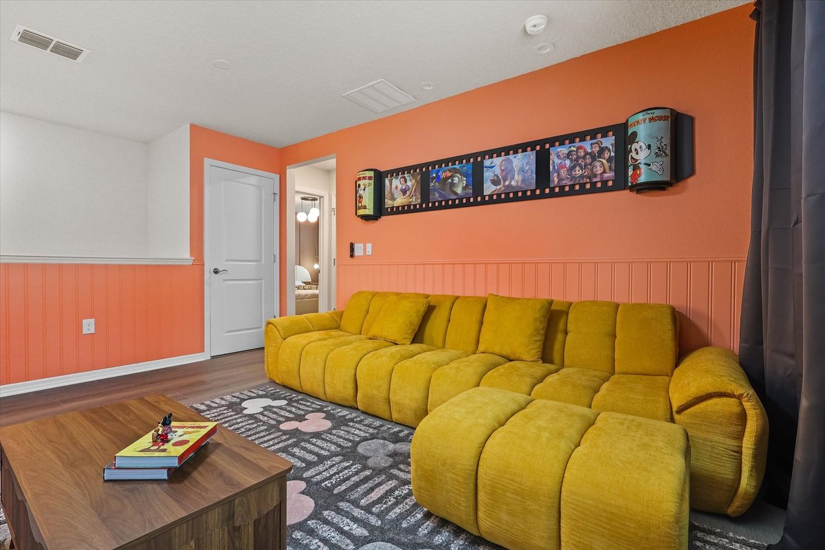 Mickey-themed lounge detail with large sectional sofa, graphic wall art and warm contemporary finishes.