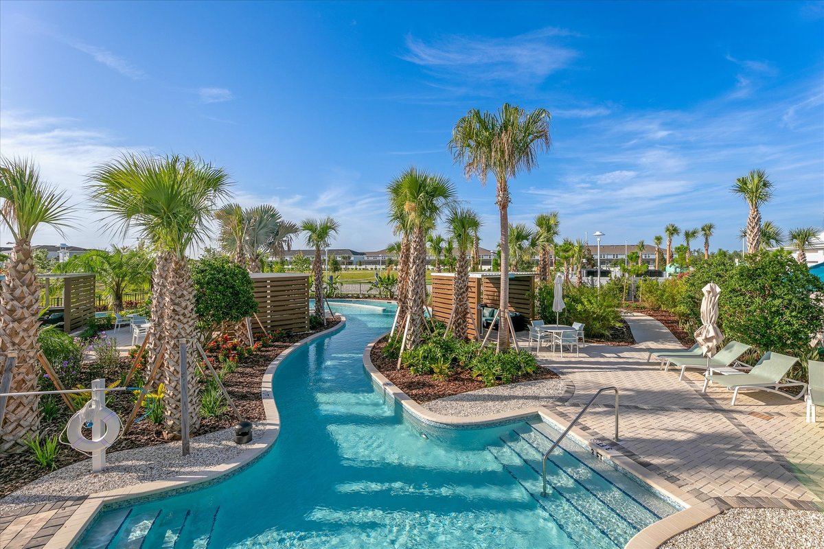Windsor Cay Resort lazy river winding through tropical landscaping, palms and poolside recreation areas.