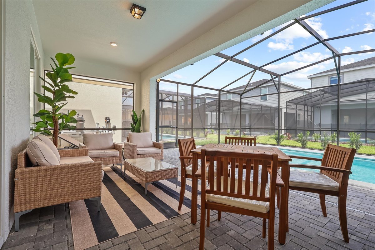Covered outdoor seating and dining area beside the screened private pool at the Clermont vacation home.
