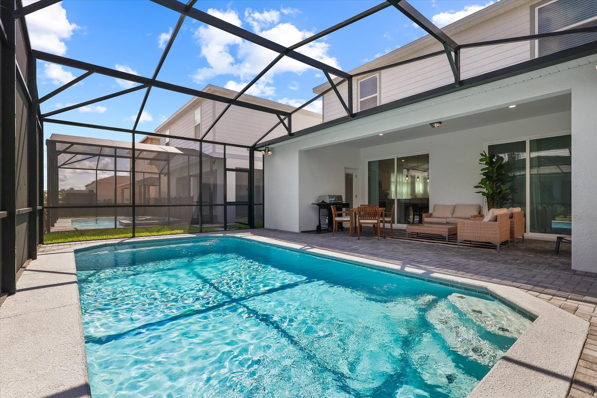 Screened private pool and covered patio with outdoor dining and lounge seating at the Windsor Cay home.