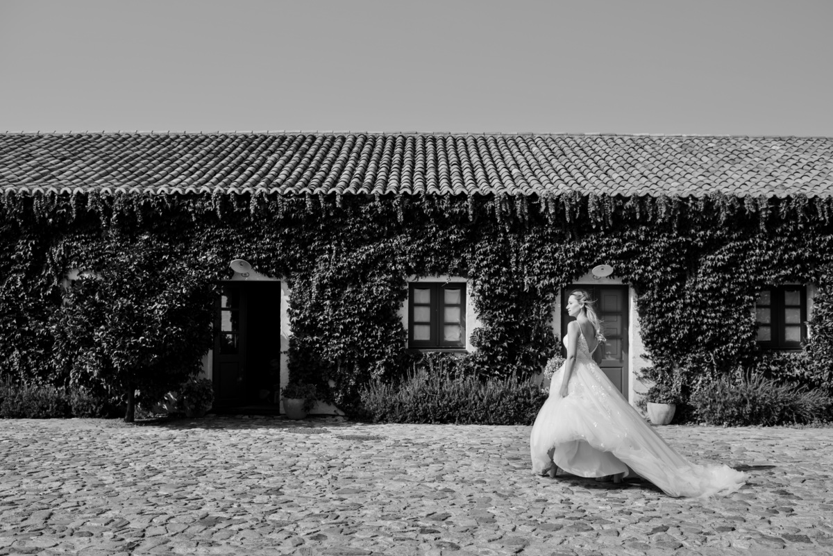 Bride walking through the gardens with bouquet and dress at São Lourenço do Barrocal wedding.