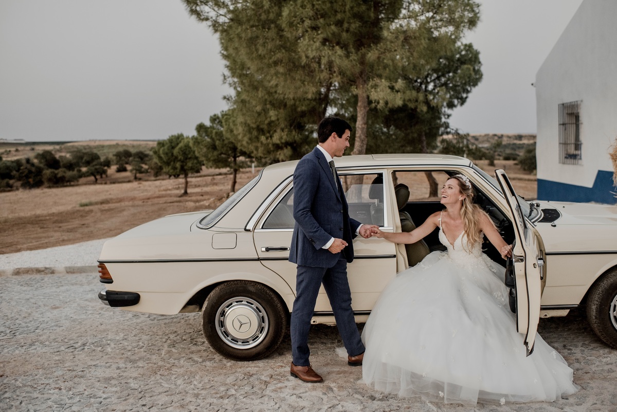 Groom holding bride’s hand as he helps her out of the car at São Lourenço do Barrocal.
