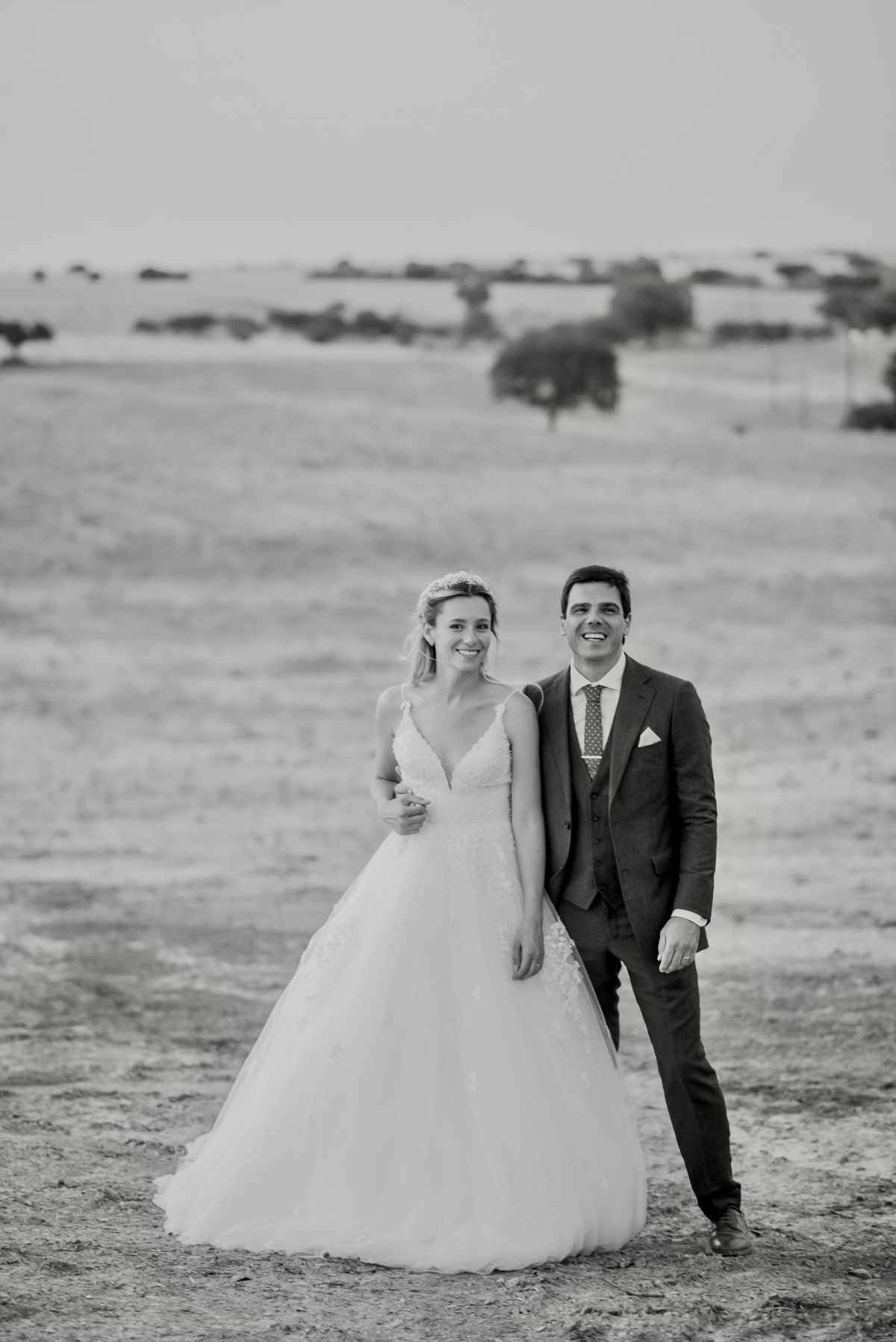 Bride and groom walking hand in hand through Alentejo countryside.