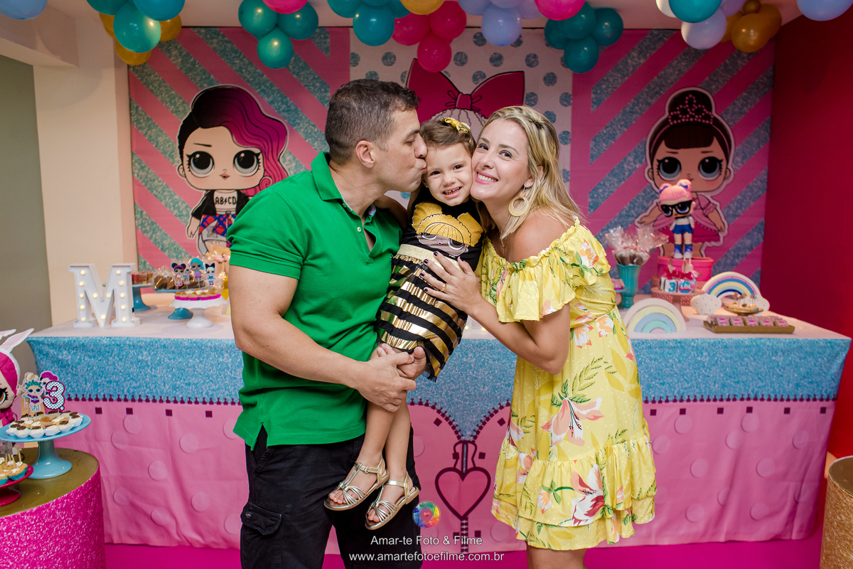 menina de 3 anos vestida de queen b em sua festa de aniversário do tema lol e abraçando os pais