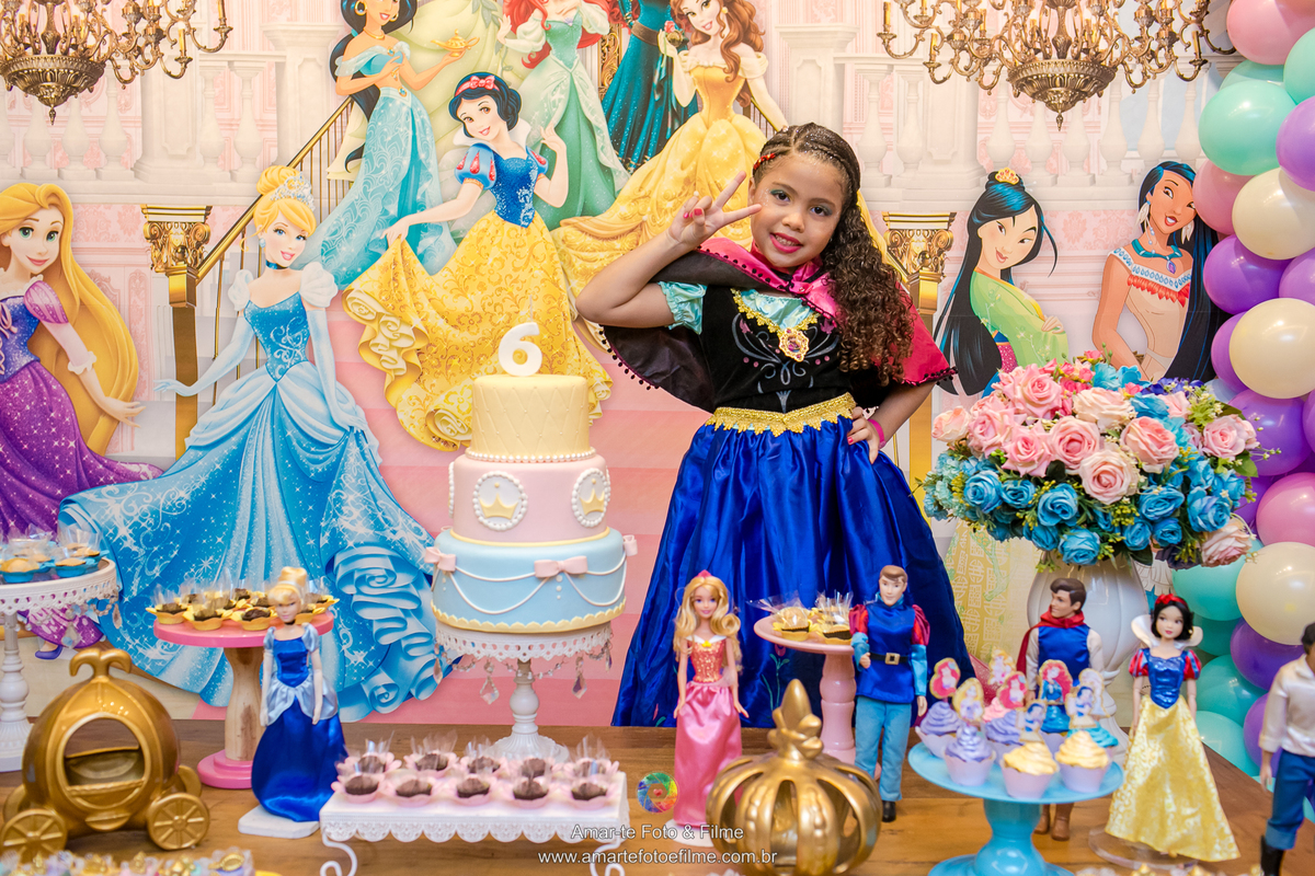 menina fazendo pose para foto na mesa do bolo princesas vestina de frozen Anna