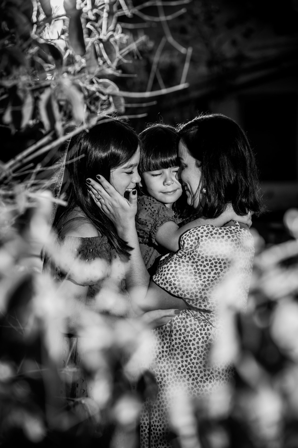 Mãe abraça filhas em meio à natureza