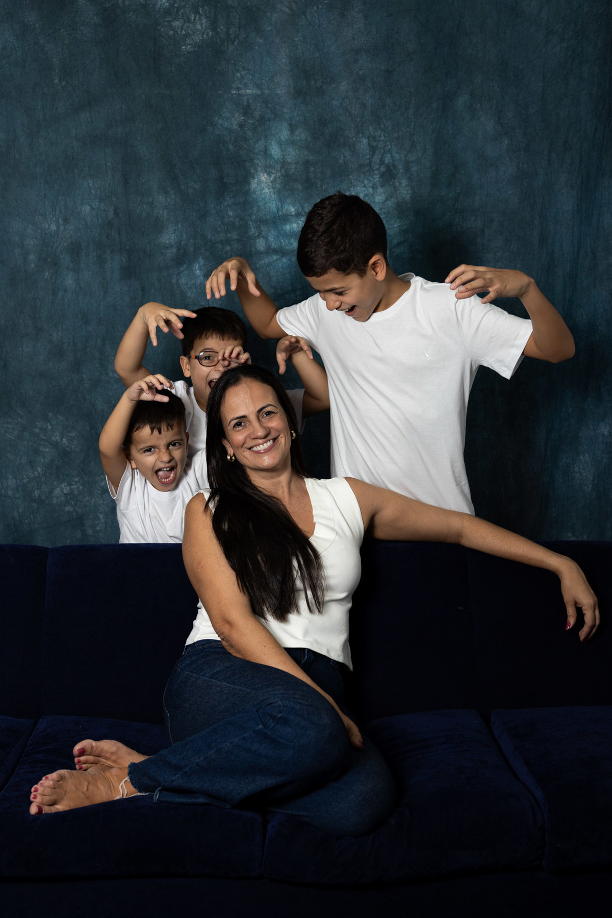 Mulher e seus três filhos fazendo pose em estúdio de fotos
