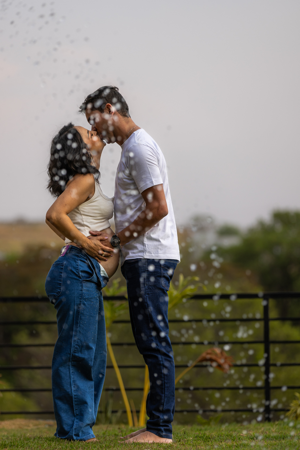 Marido e mulher se beijam acariciando barriga gestante