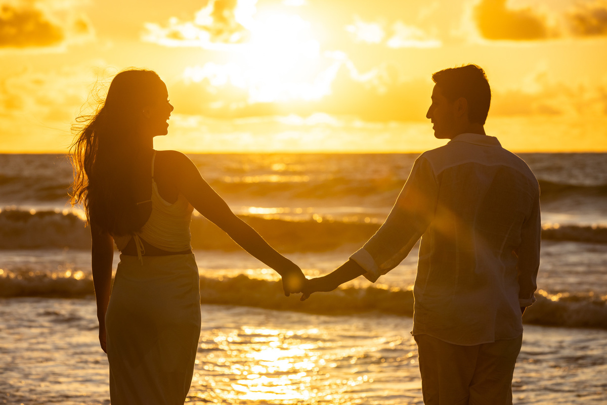 Homem e mulher se olhando com o por do sol ao fundo