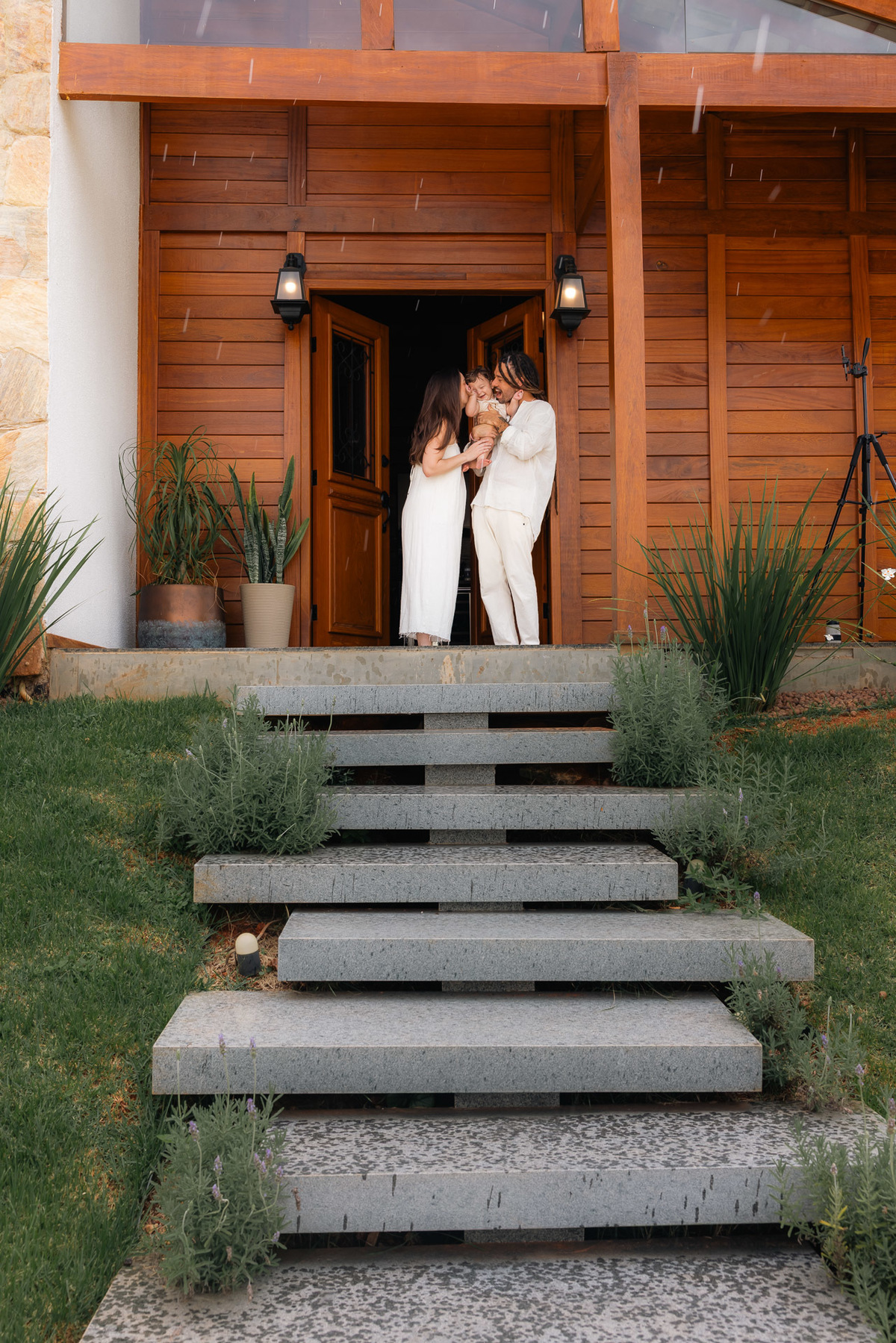 Família na porta de casa durante chuva