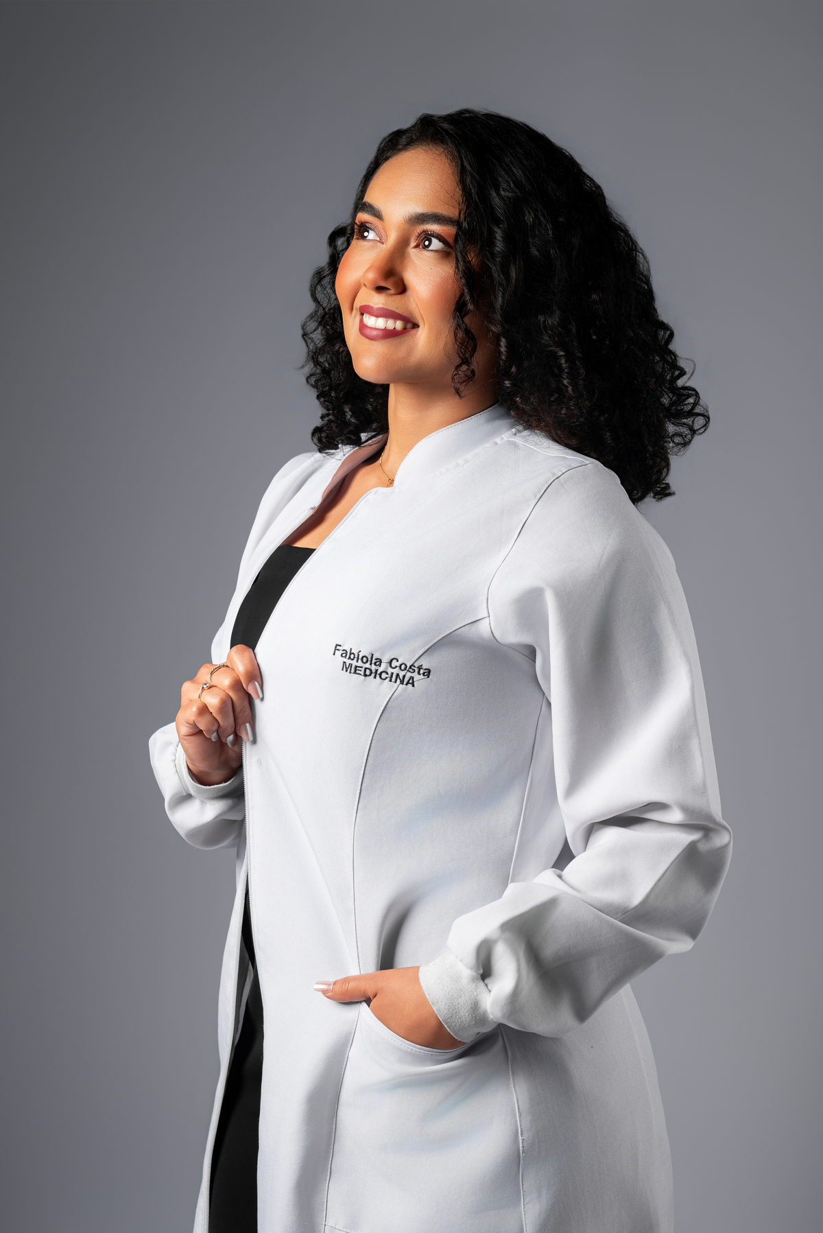 Médica recém-formada em ensaio fotográfico profissional usando jaleco, em estúdio com fundo neutro, em Guajará-Mirim RO e Guayaramerín Bolívia.