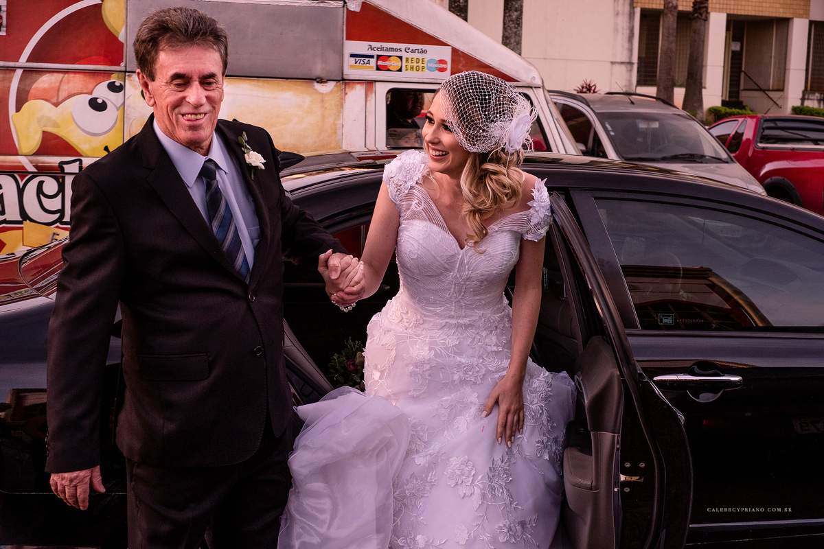 noiva saindo do carro com o pai na paroquia divino espirito santo em Brasilia