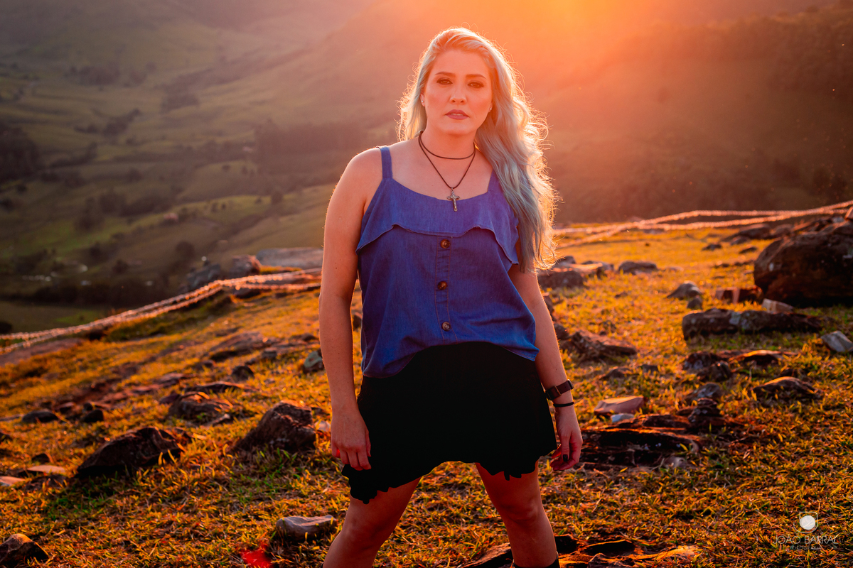 mulher de cabelo azul posando para foto no por do sol em ensaio fotográfico morro do gavião no paraná pelo fotógrafo joão barral