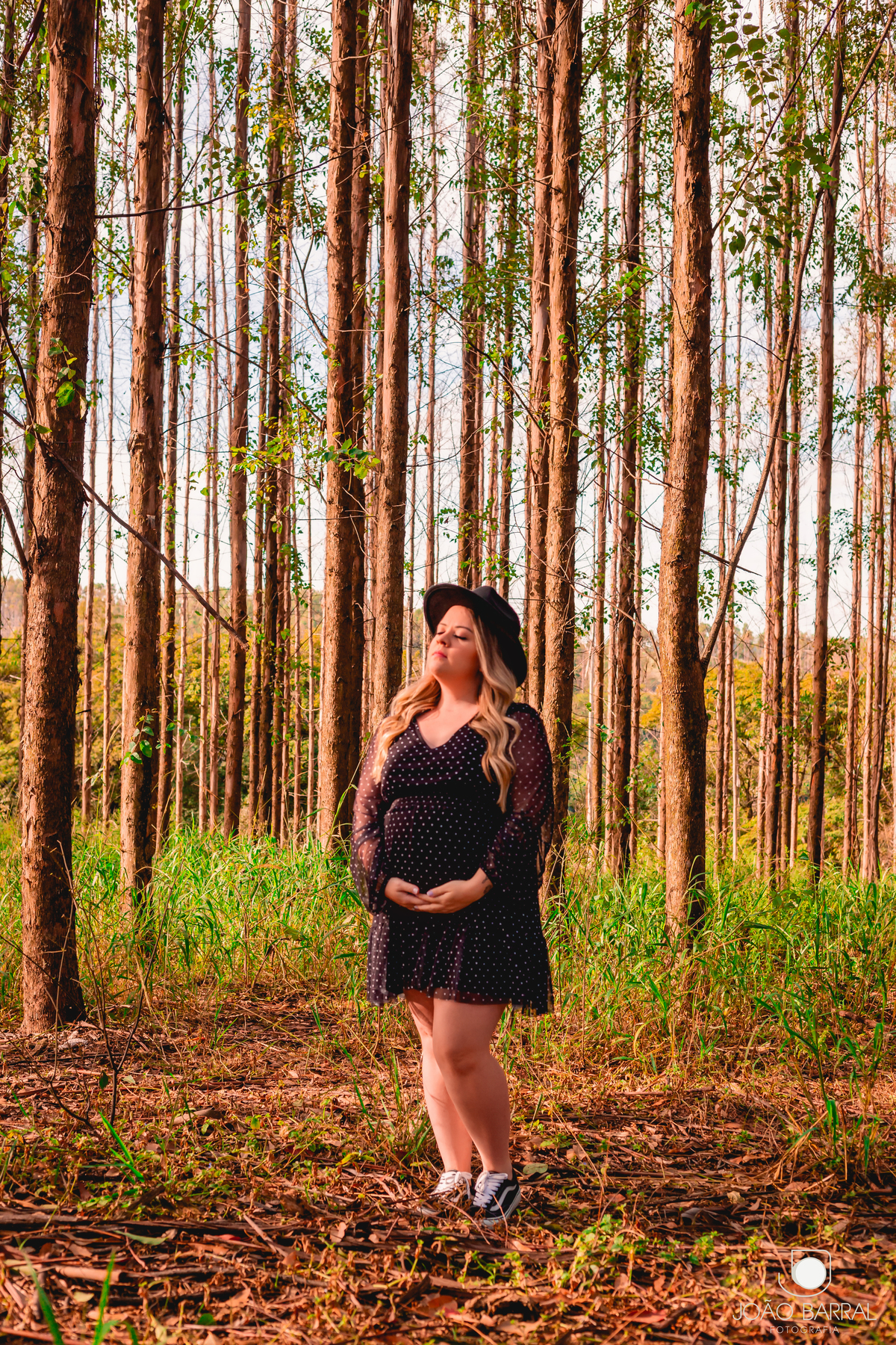 ensaio de mulher gestante em campo aberto com chapéu e roupas pretas