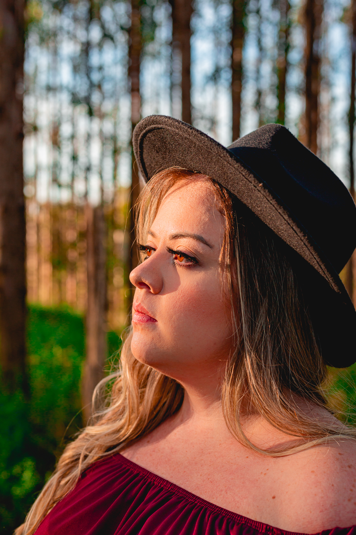 olhar de mulher gestante em campo aberto com chapéu e vestido vermelho