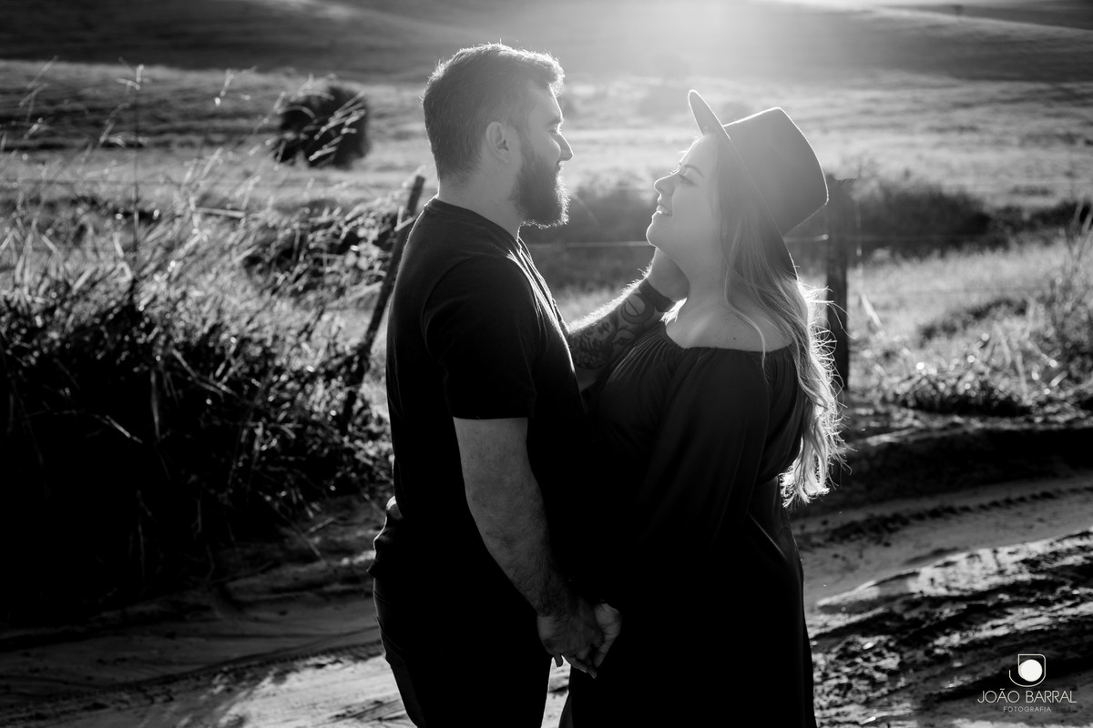 foto em preto e branco de casal gestante no por do sol em um campo