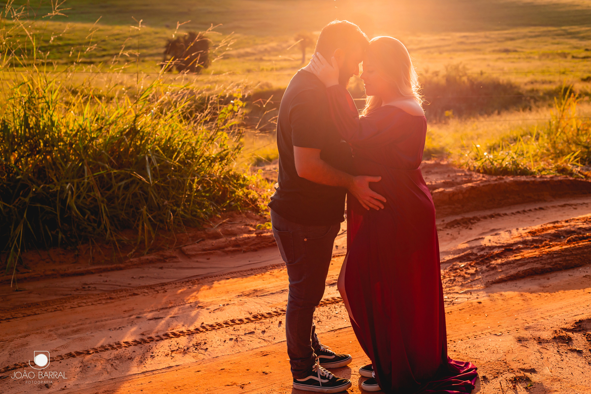 foto de casal gestante no por do sol em um campo