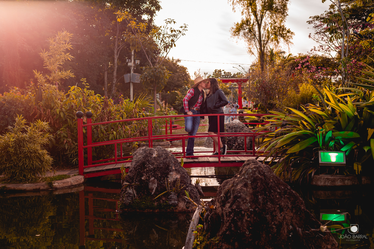 casal gay de mulheres se beijando em ponte vermelha sobre o lago municipal