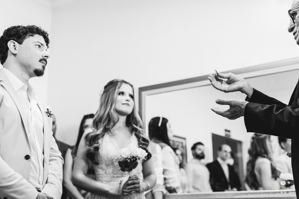 família reunida em cartório rindo em casamento civil com juiz mostrando aliança