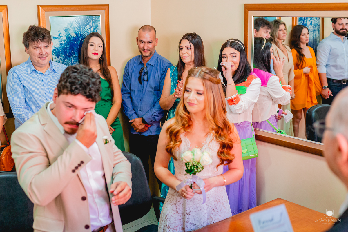 noivo limpando o choro emocionado em casamento civil no cartório com família em volta
