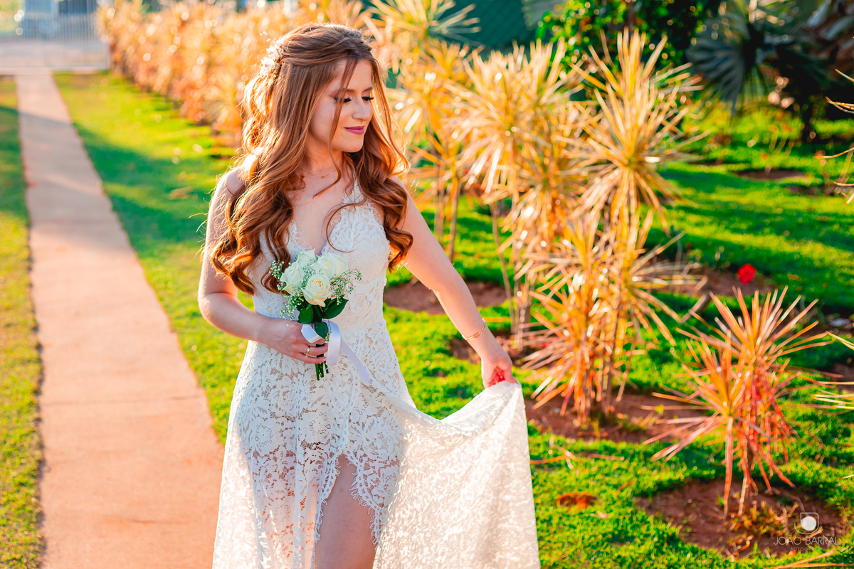 noiva segurando vestido e buquê com jardim  