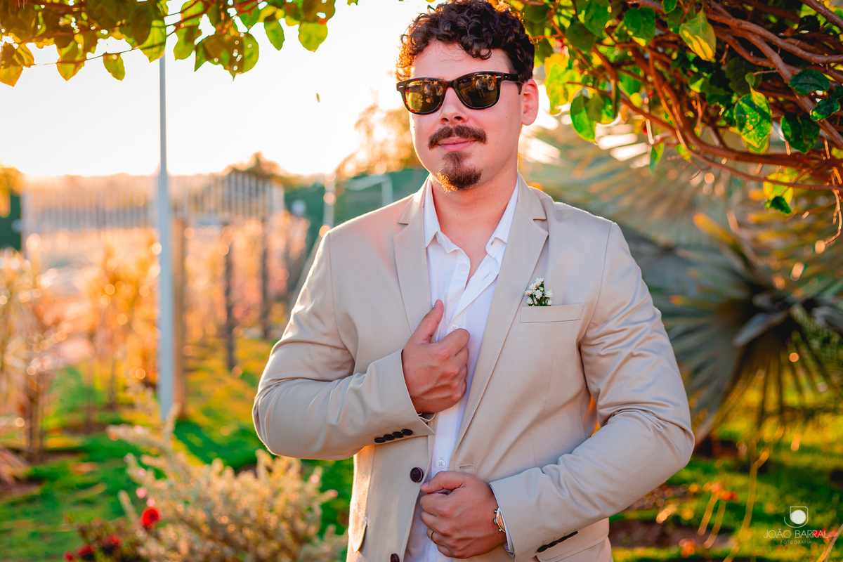 noivo de óculos sorrindo em jardim