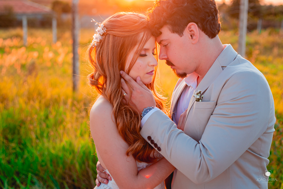 casal de noivos abraçados em jardim com por do sol