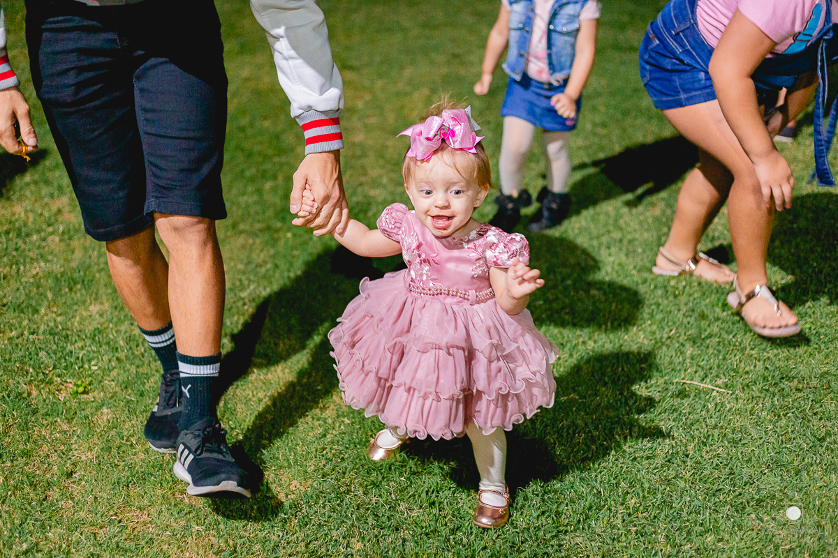 criança andando acompanhada de adulto em festa de aniversário infantil