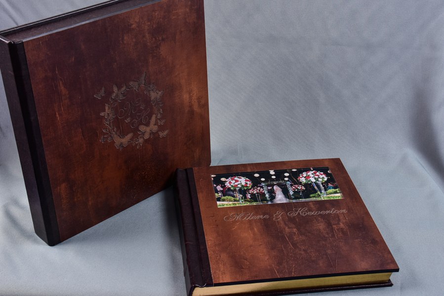 Álbum 30x60 e outros tamanhos, capa com visor de foto em papel metalizado e protegida por acrílico, feito em madeira, com pintura dourada nas páginas, nome dos noivos entalhado a laser e caixa com a logo dos noivos entalhada a laser