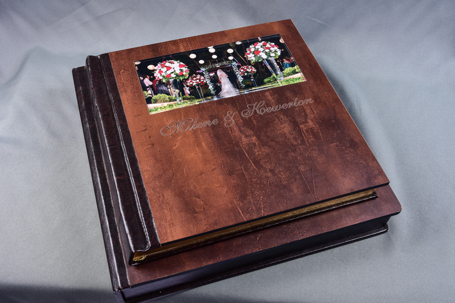 Álbum 30x60 e outros tamanhos, capa com visor de foto em papel metalizado e protegida por acrílico, feito em madeira, com pintura dourada nas páginas, nome dos noivos entalhado a laser e caixa com a logo dos noivos entalhada a laser