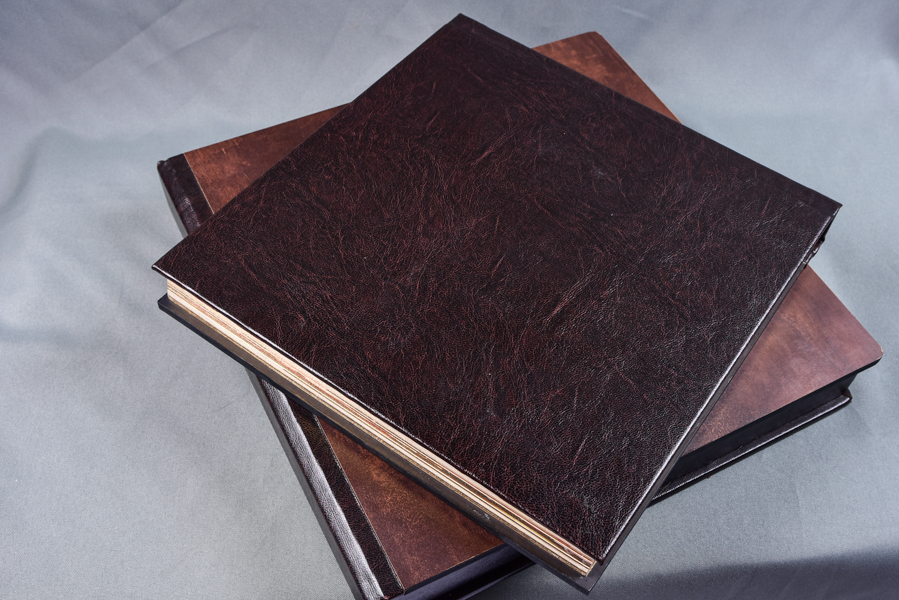 Álbum 30x60 e outros tamanhos, capa com visor de foto em papel metalizado e protegida por acrílico, feito em madeira, com pintura dourada nas páginas, nome dos noivos entalhado a laser e caixa com a logo dos noivos entalhada a laser