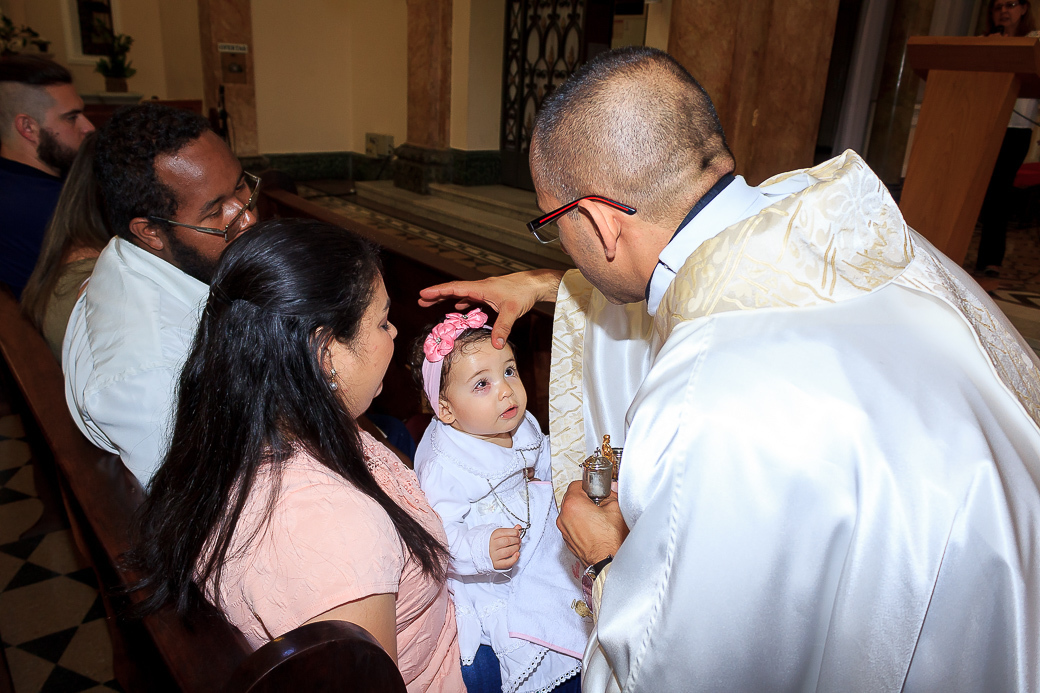 padre abençoando criança batizado