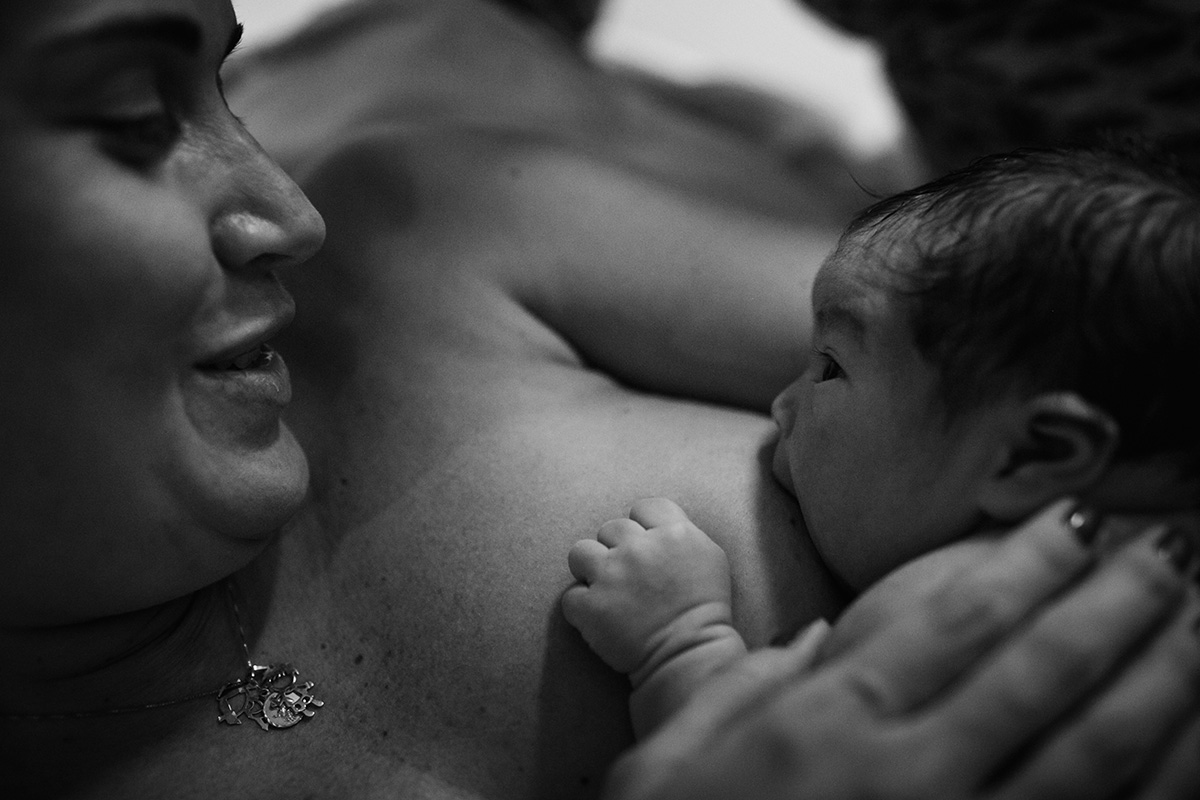 bebê olha nos olhos da mãe durante seu primeiro aleitamento em foto feita por adrianacostafotos